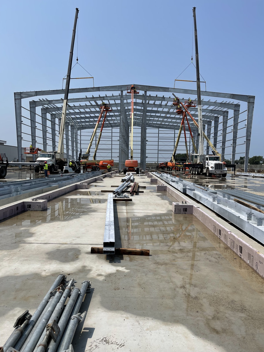 Cranes and lifts setting pre-engineered steel frames on a layer facility jobsite in Iowa