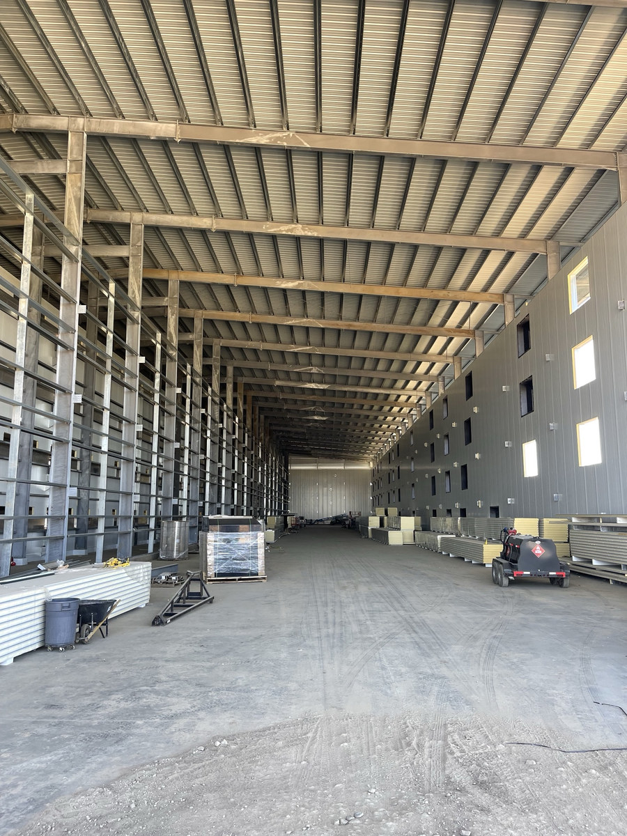 Interior of a large pre-engineered metal layer building showing steel framing and insulated wall panels