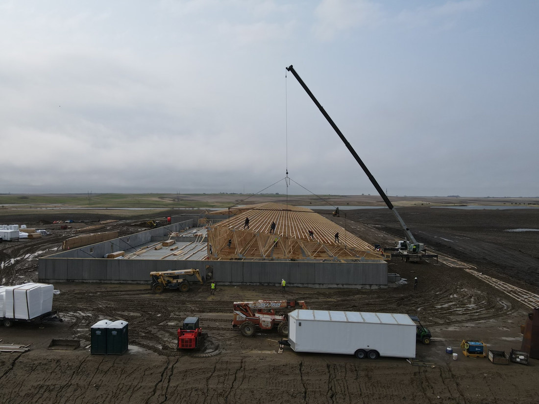 Crew on roof trusses lifted by crane at a South Dakota wood frame ag building